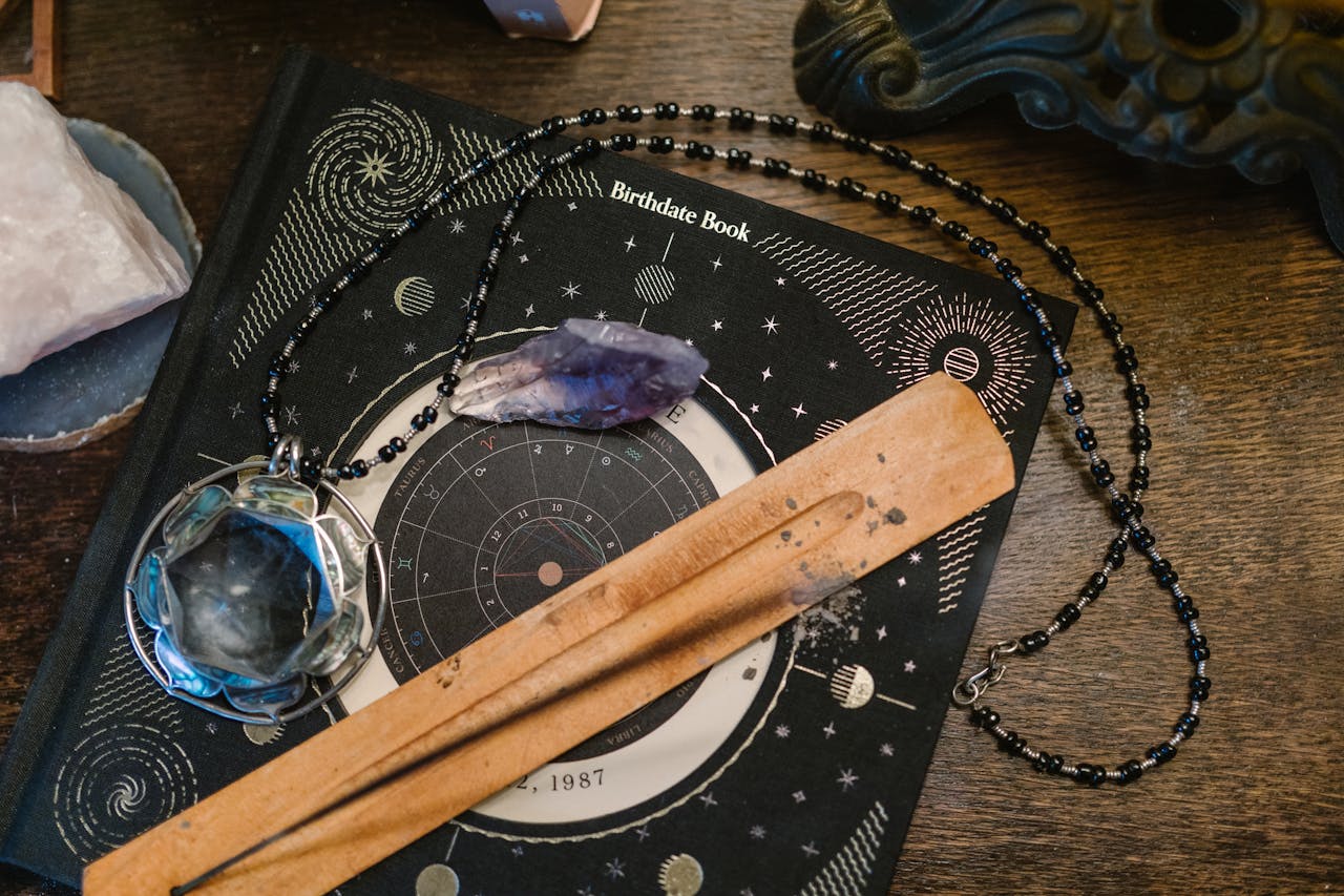 Mastering the First Impression: Your intriguing post title goes here Astrology-themed flat lay featuring a birthdate book, crystals, and necklace on a wooden surface.